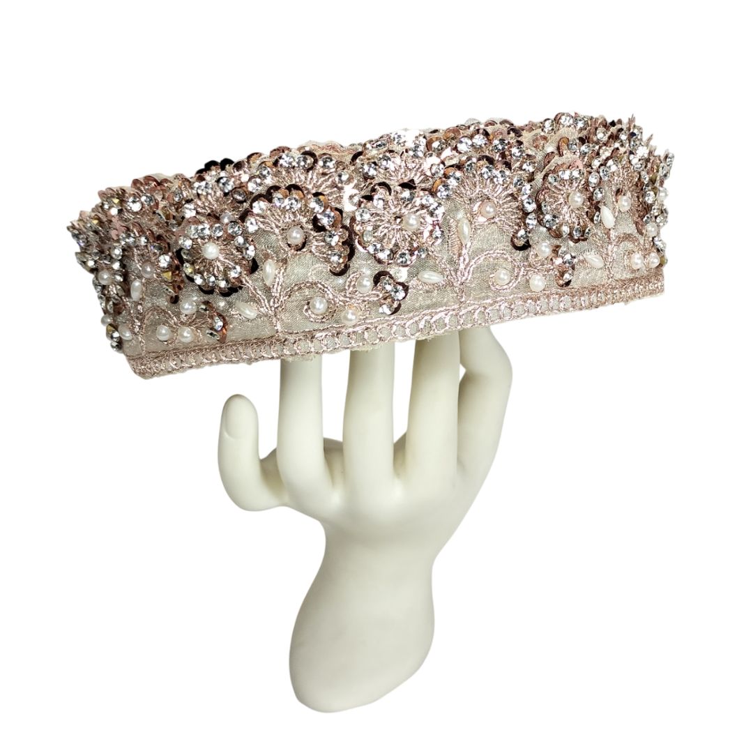 Decorative headband with floral embellishments on a white mannequin hand