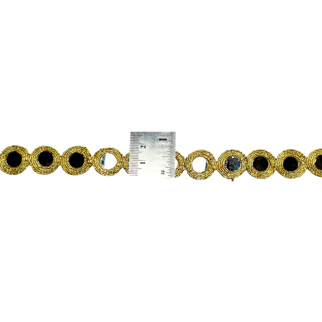 Gold bracelet with black stones and a ruler for scale on a white background