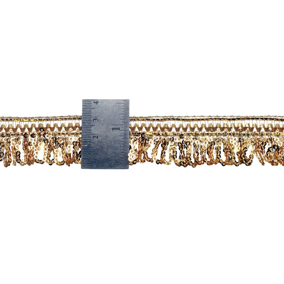 Gold fringe trim with a ruler for scale on a white background