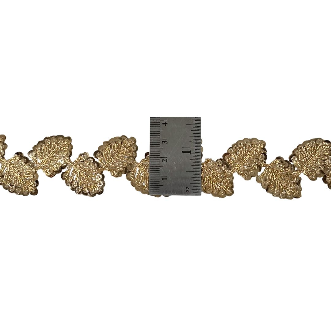 Decorative gold leaf trim with a ruler for scale on a white background