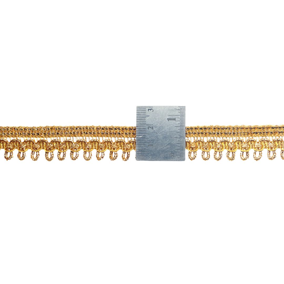 Gold fringe trim with a ruler for scale on a white background