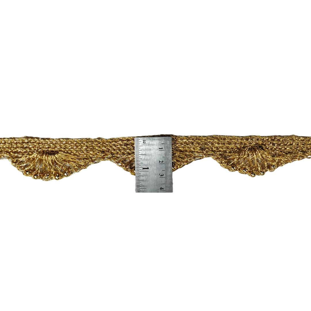 Gold lace trim with a ruler for scale on a white background