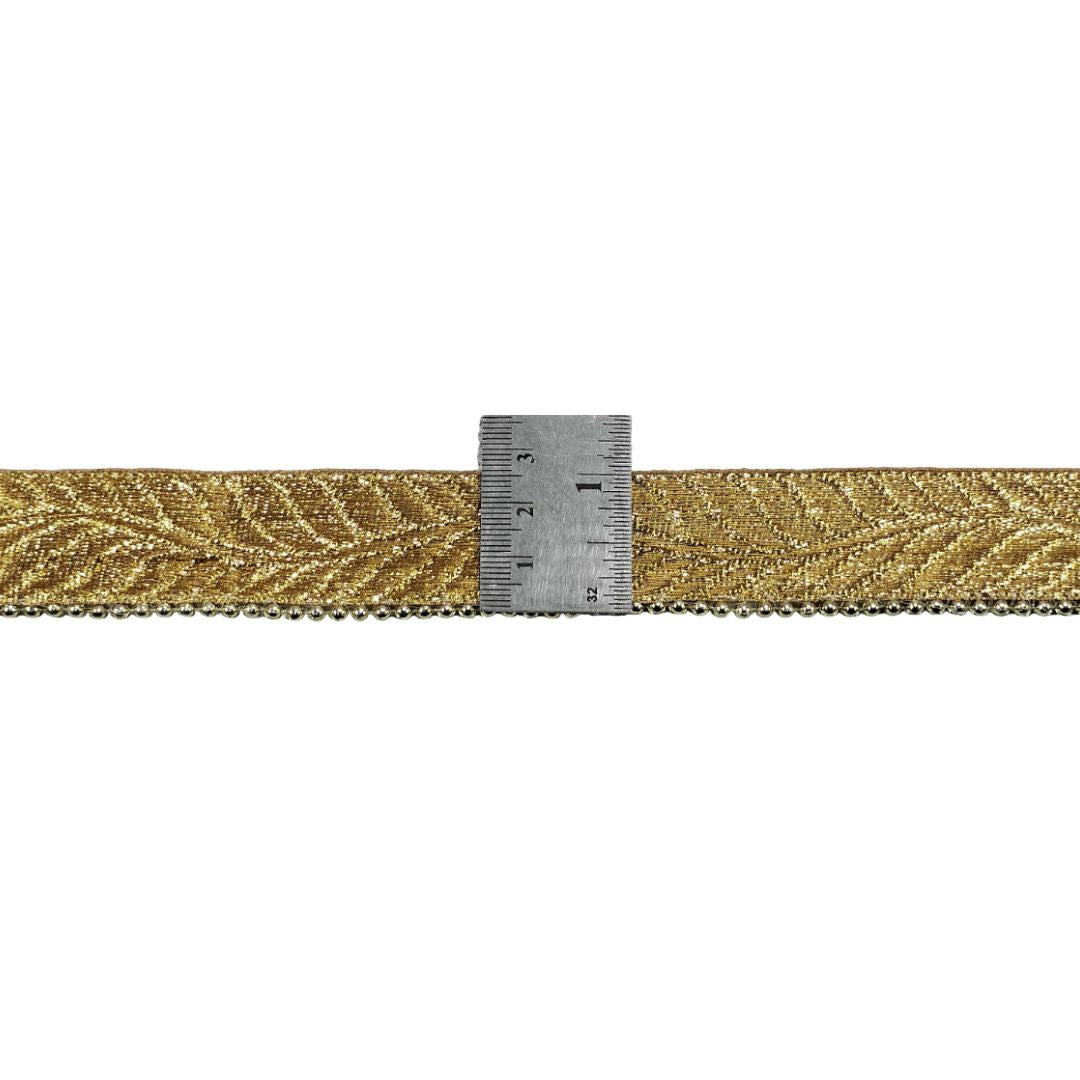 Gold woven ribbon with a ruler for scale on a white background