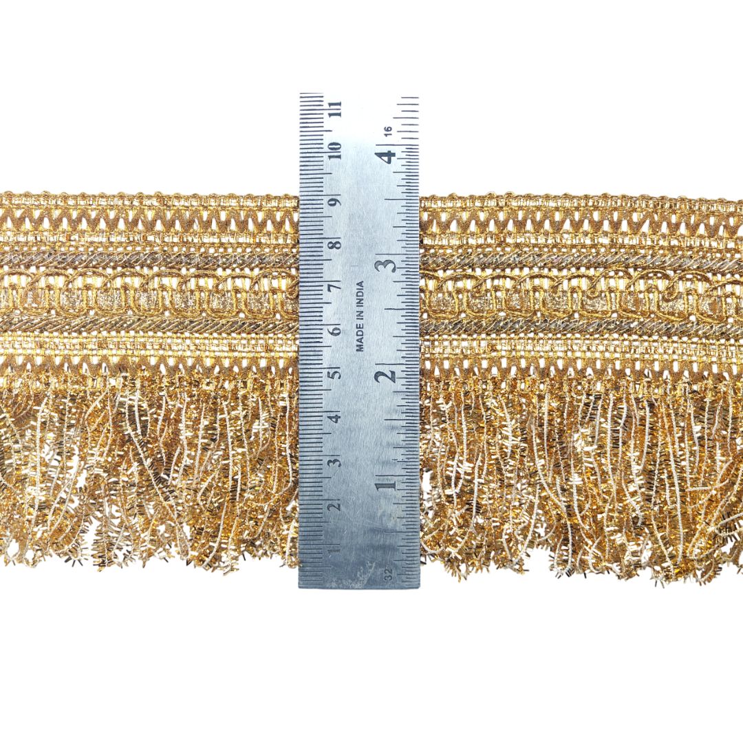 Gold fringe fabric with a ruler for scale on a white background