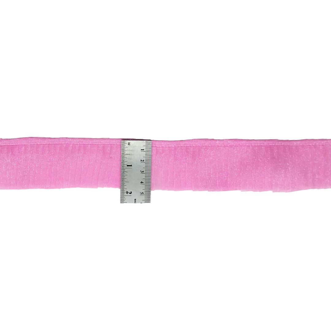 Pink ribbon with a ruler for scale on a white background
