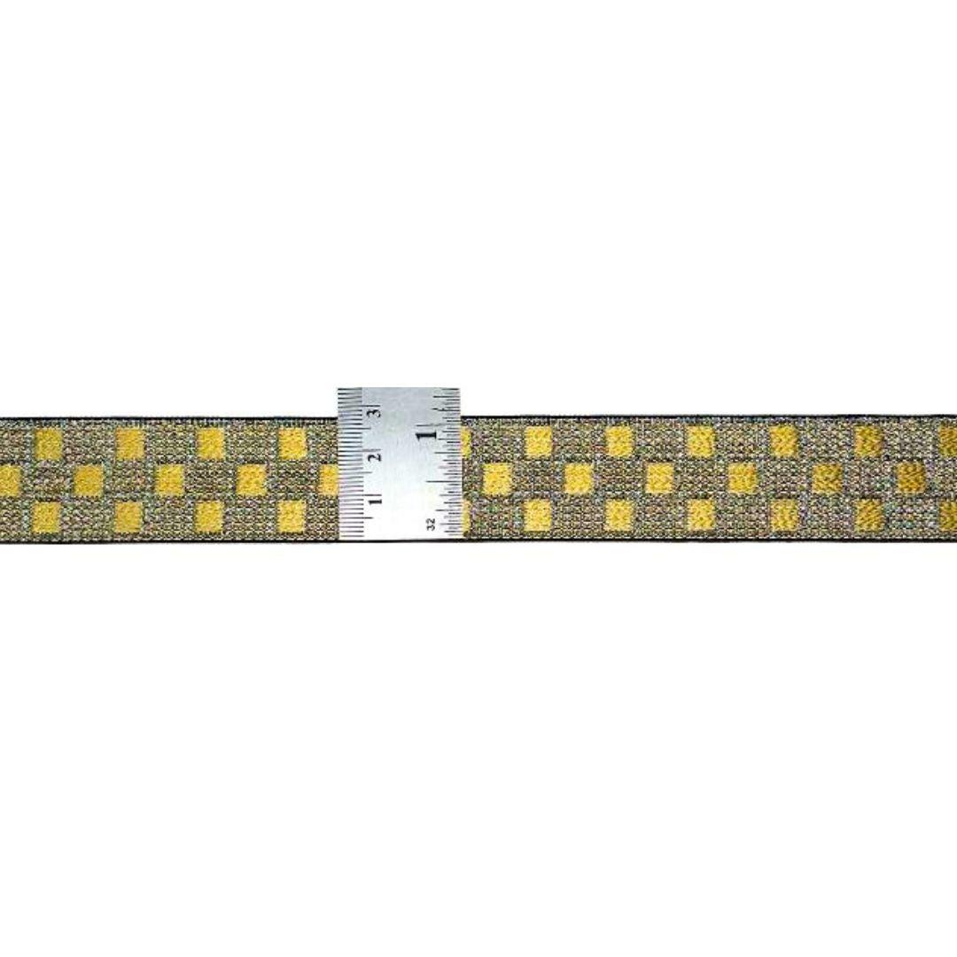 Fabric strip with yellow square pattern and a ruler for scale on a white background