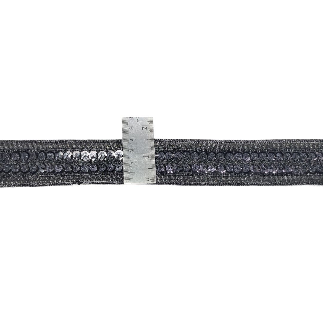 Black elastic band with silver sequins and a ruler for scale on a white background