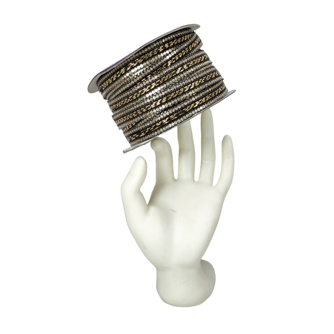 Spool of metallic ribbon on a mannequin hand against a white background