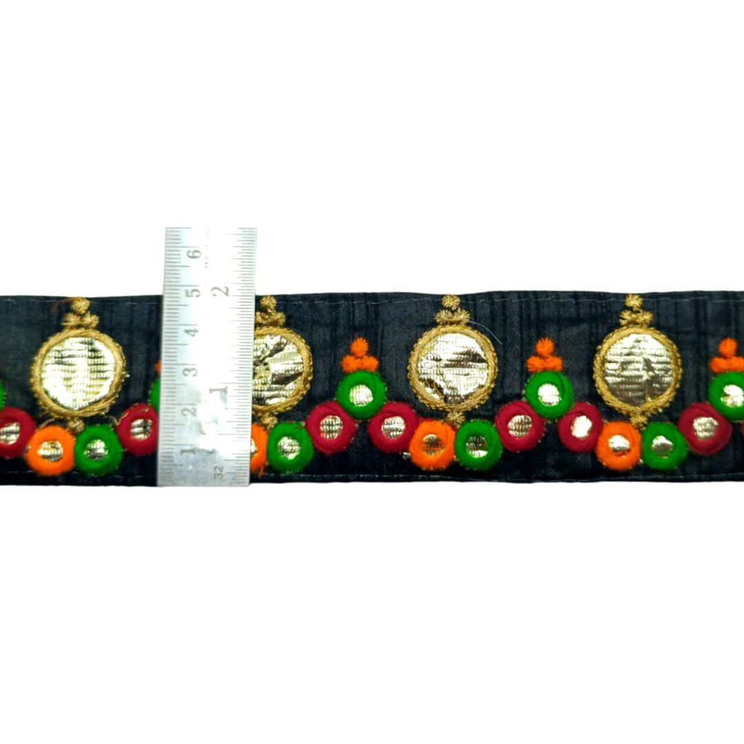 Decorative ribbon with gold, green, and orange elements next to a ruler for measurement.