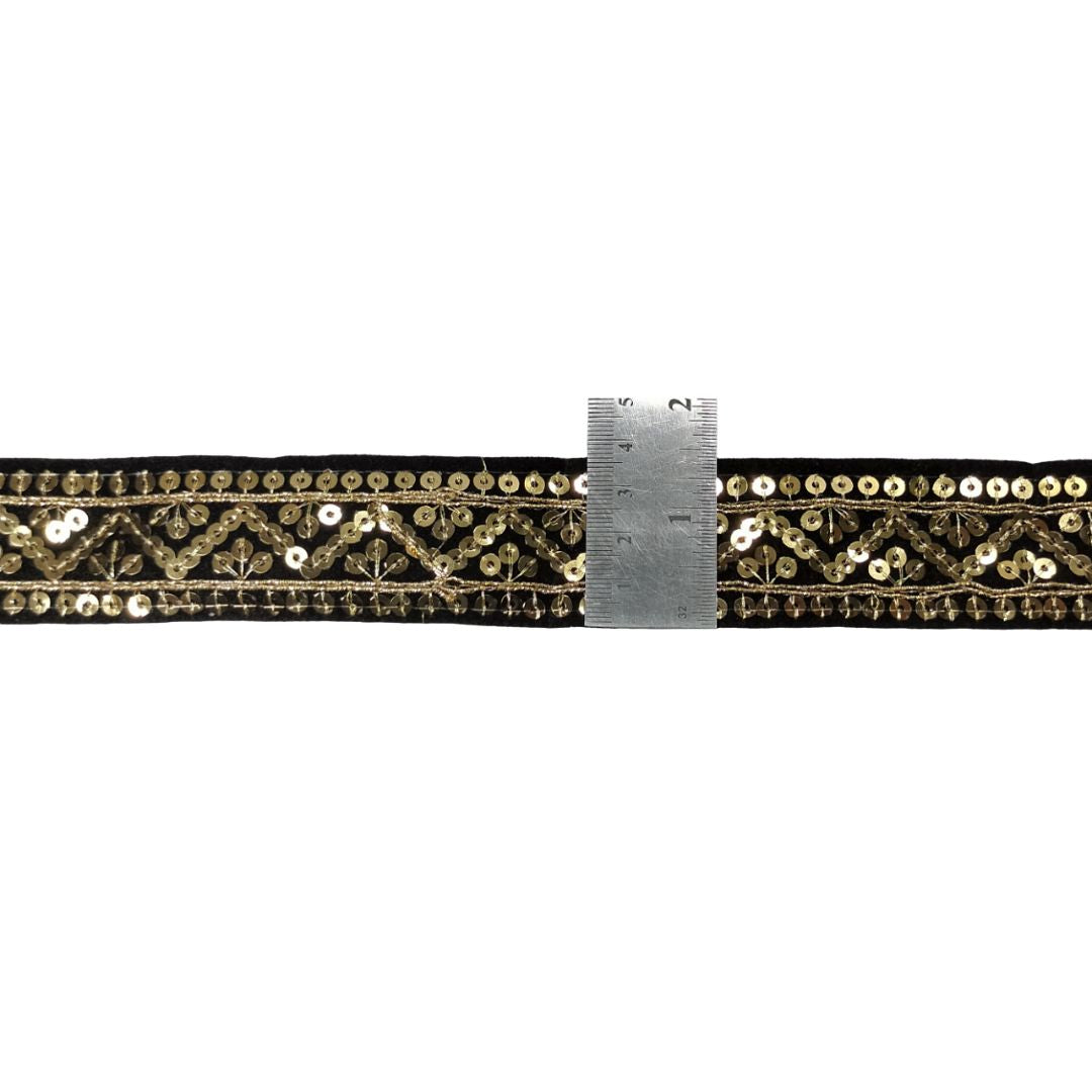 Decorative ribbon with gold sequins and a ruler for scale on a white background