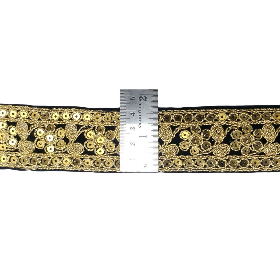 Decorative black ribbon with gold embroidery and sequins, measured against a ruler.