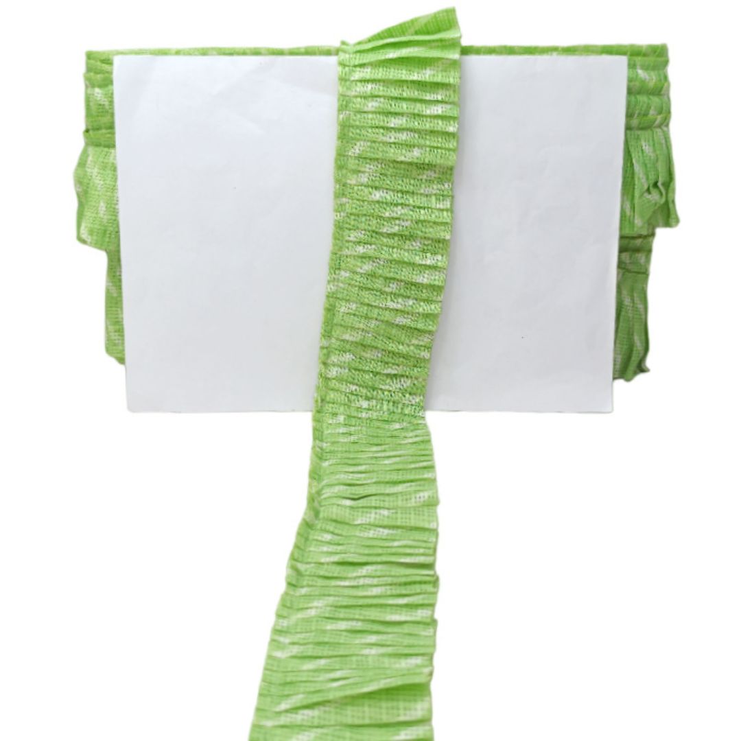 Green pleated fabric with white paper on a white background