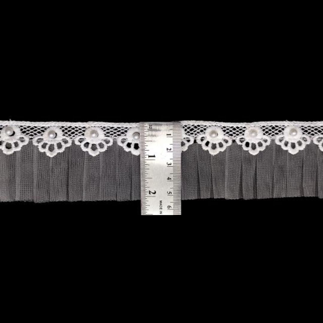 Decorative lace trim with a ruler for scale on a black background