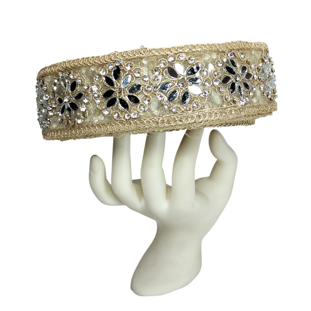 Decorative headband with floral patterns and crystals on a white mannequin hand.