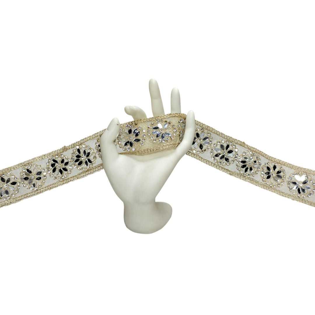 Decorative ribbon with floral and crystal design held by a mannequin hand on a white background