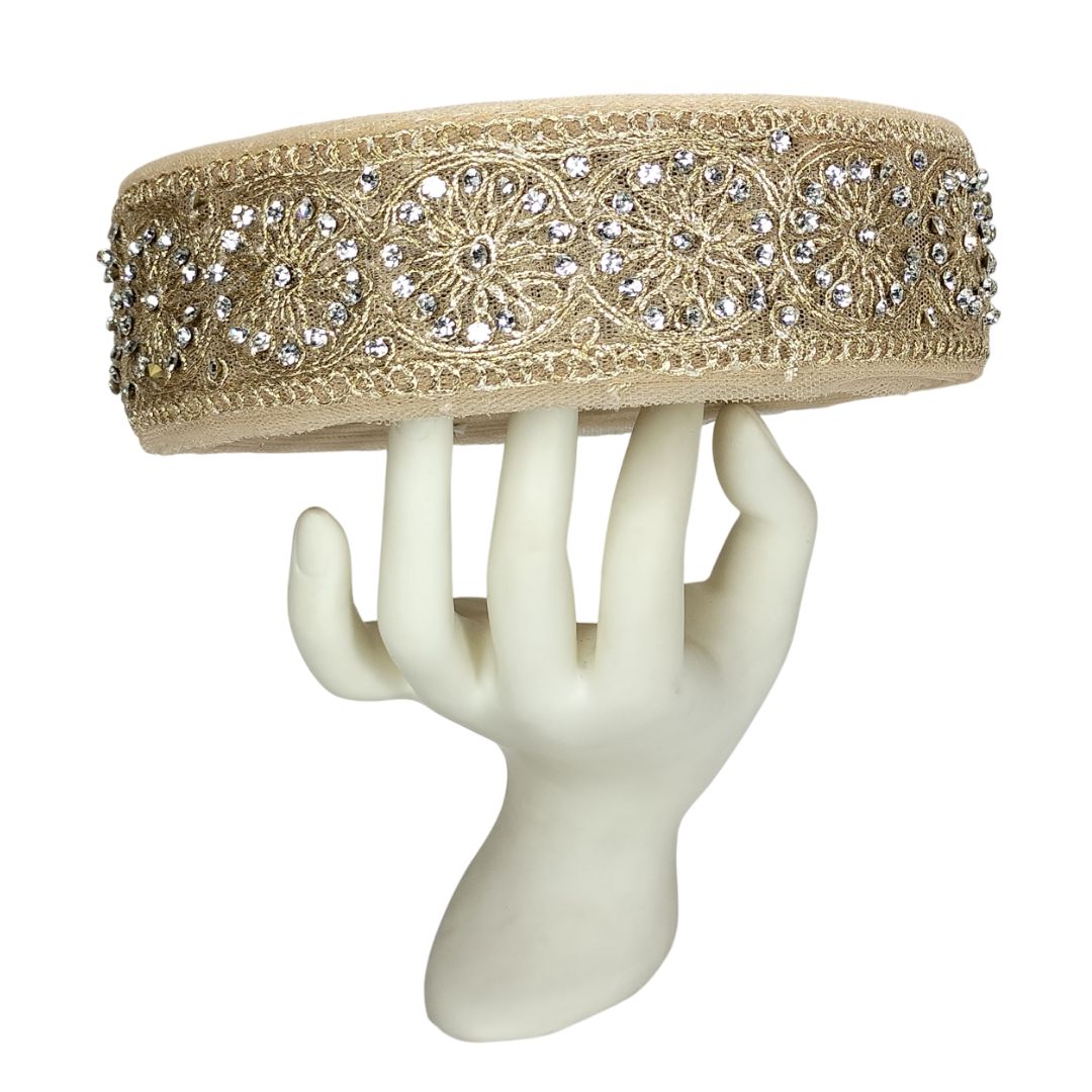 Decorative headband with intricate patterns and embellishments on a white mannequin hand.