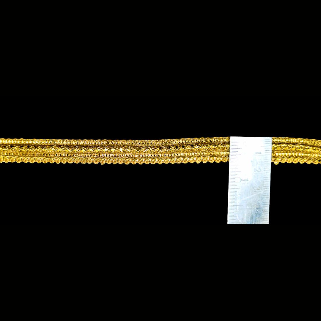 Gold bracelet with a ruler for scale on a black background
