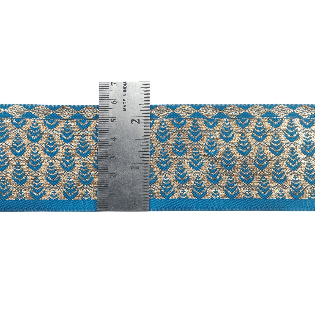 Blue and gold patterned ribbon with a ruler for scale on a white background