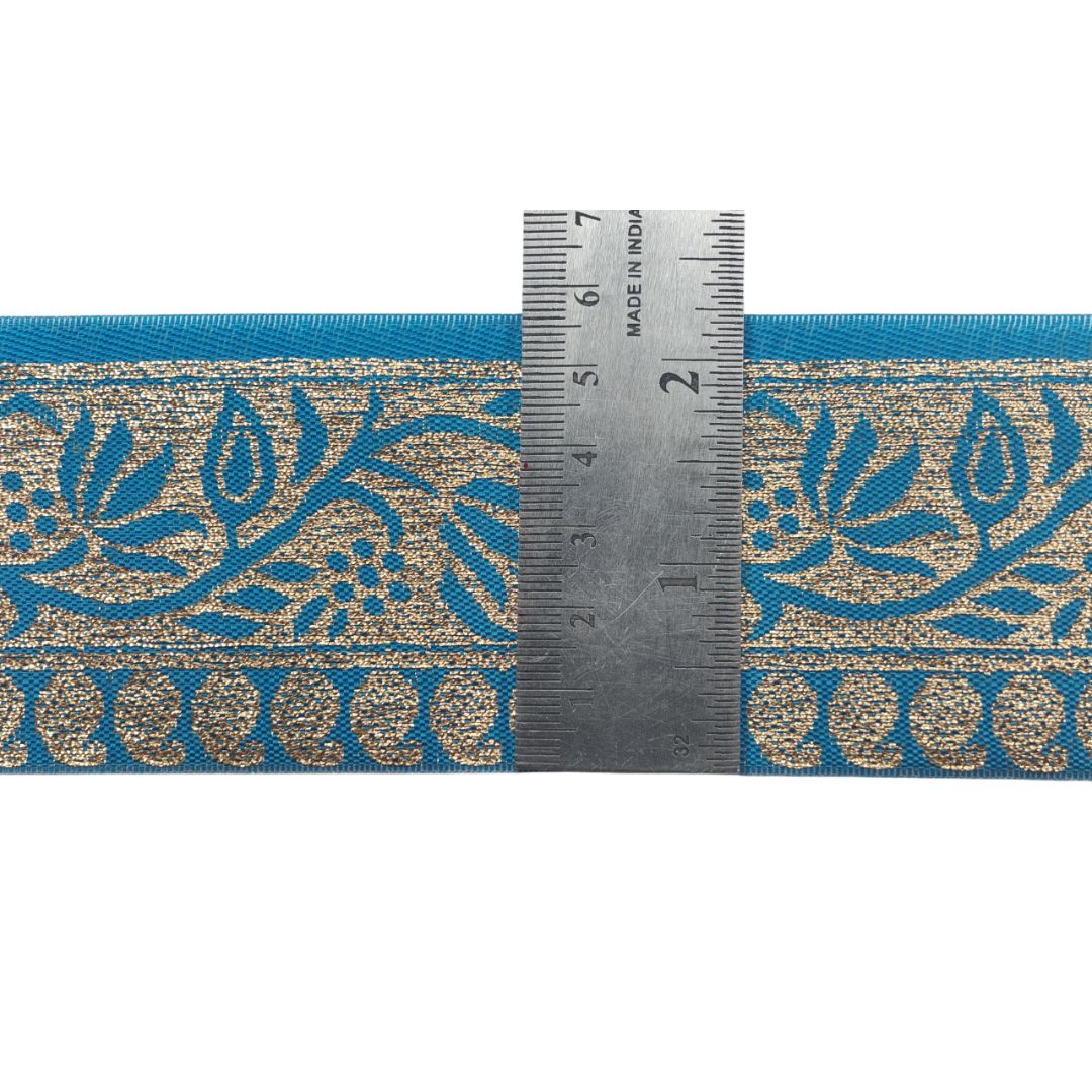 Teal ribbon with gold floral pattern and a ruler for scale on a white background