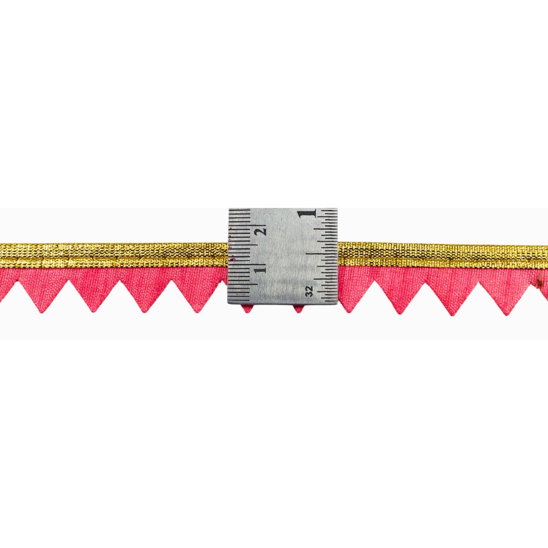 Gold and pink fabric trim with a ruler for measurement on a white background