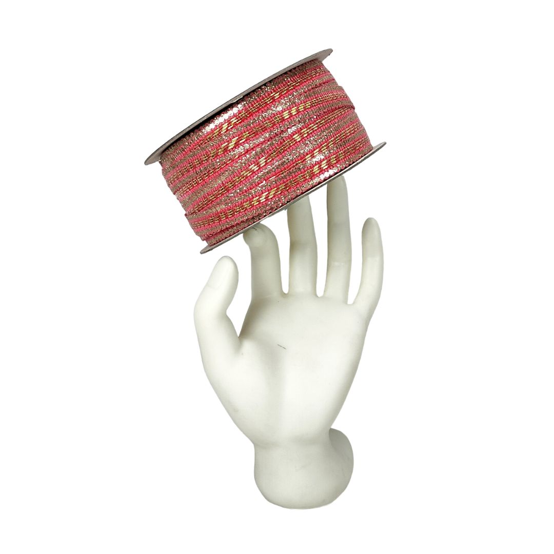 Spool of red and gold ribbon on a white mannequin hand