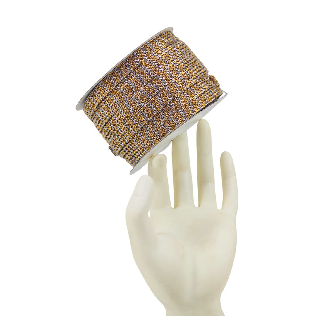 Spool of gold and gray thread on a mannequin hand against a white background