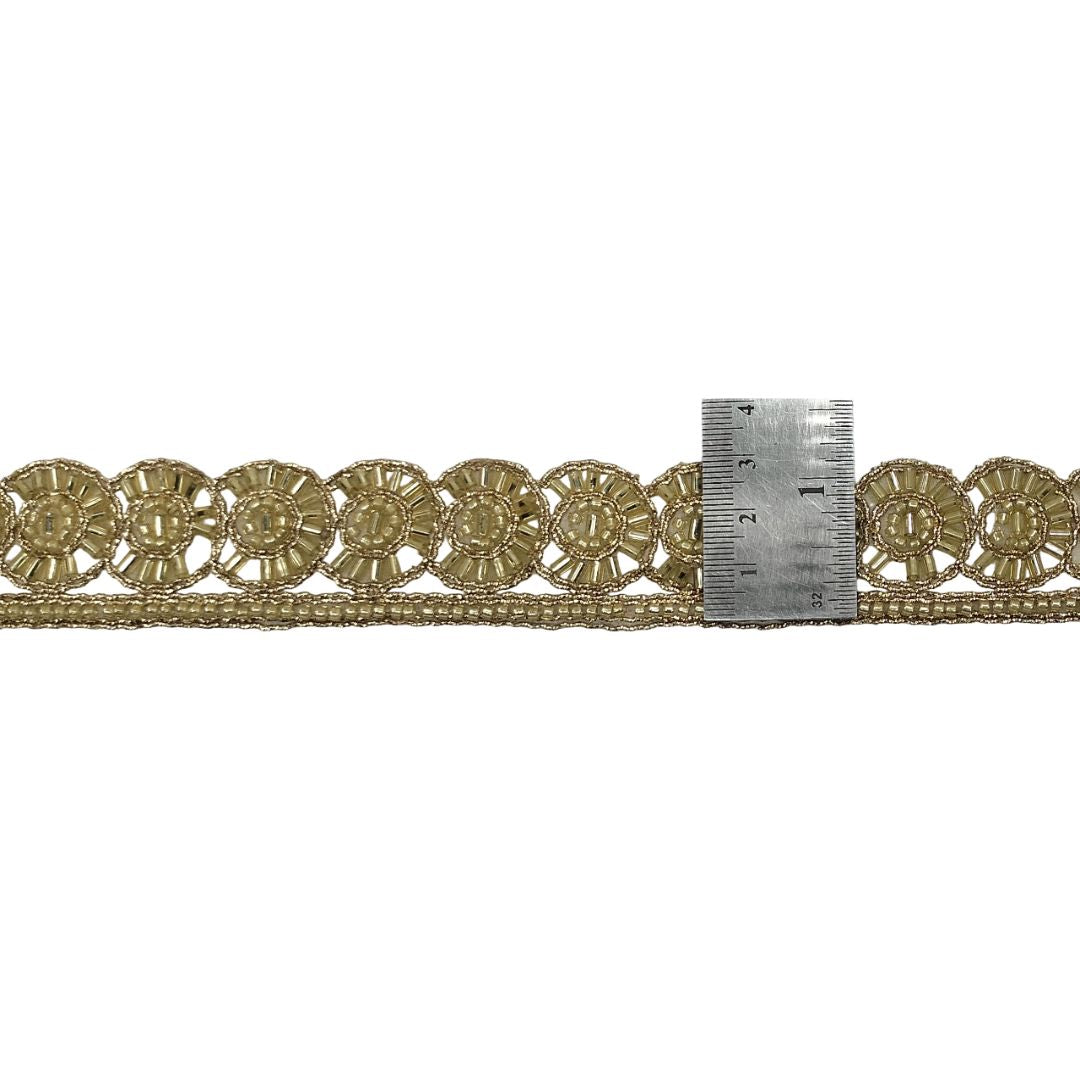 Decorative gold lace trim with a ruler for scale on a white background