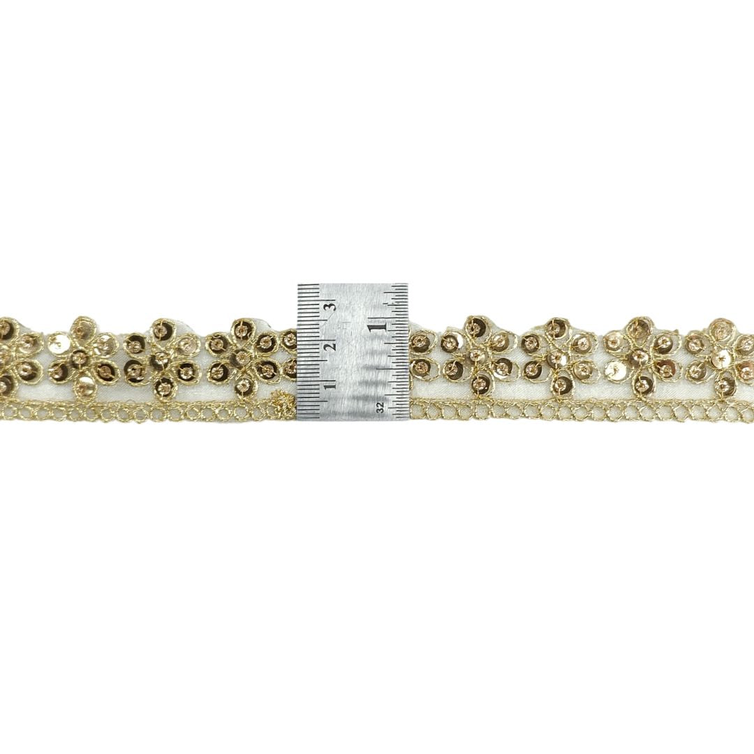 Decorative trim with gold embellishments and a ruler for scale on a white background