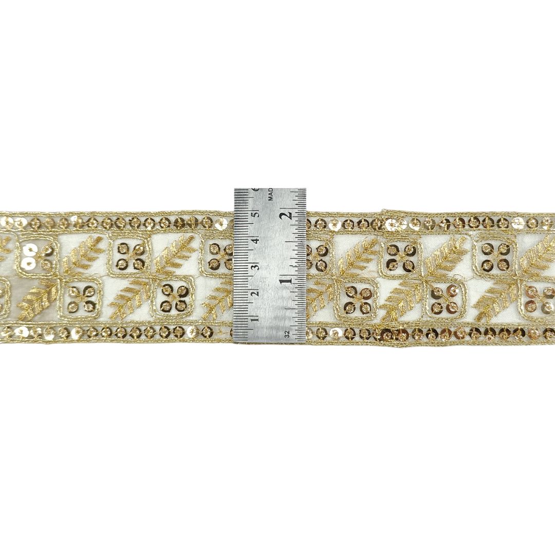 Decorative gold and white trim with a ruler for scale on a white background