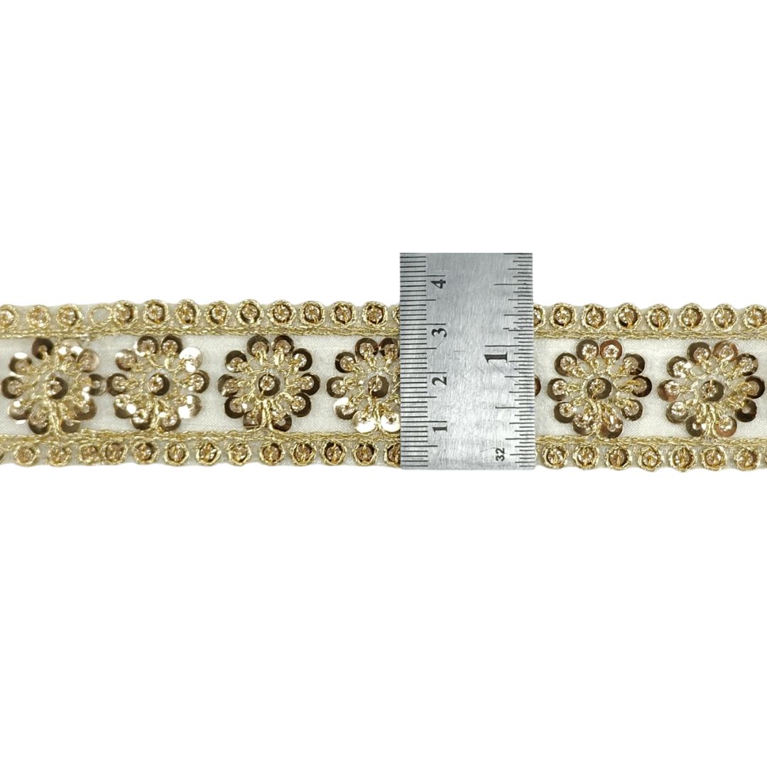 Decorative gold trim with floral patterns and a ruler for scale on a white background