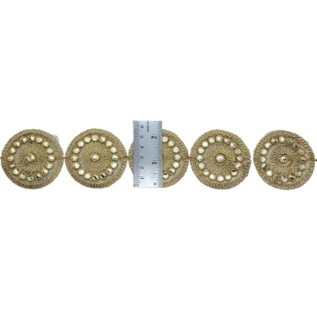 Decorative gold circular embellishments with a ruler for scale on a white background