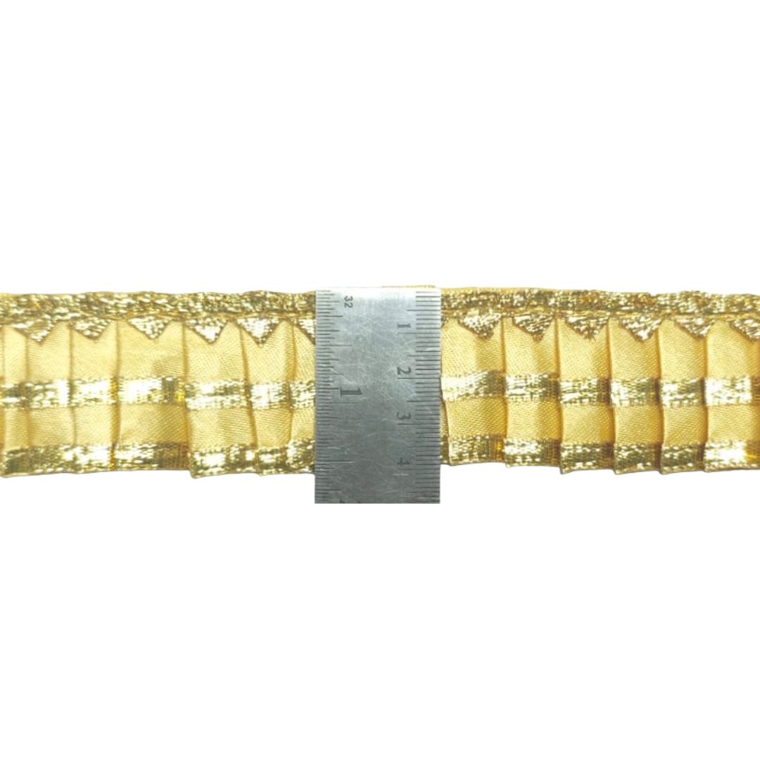 Gold lace trim with a ruler for measurement on a white background