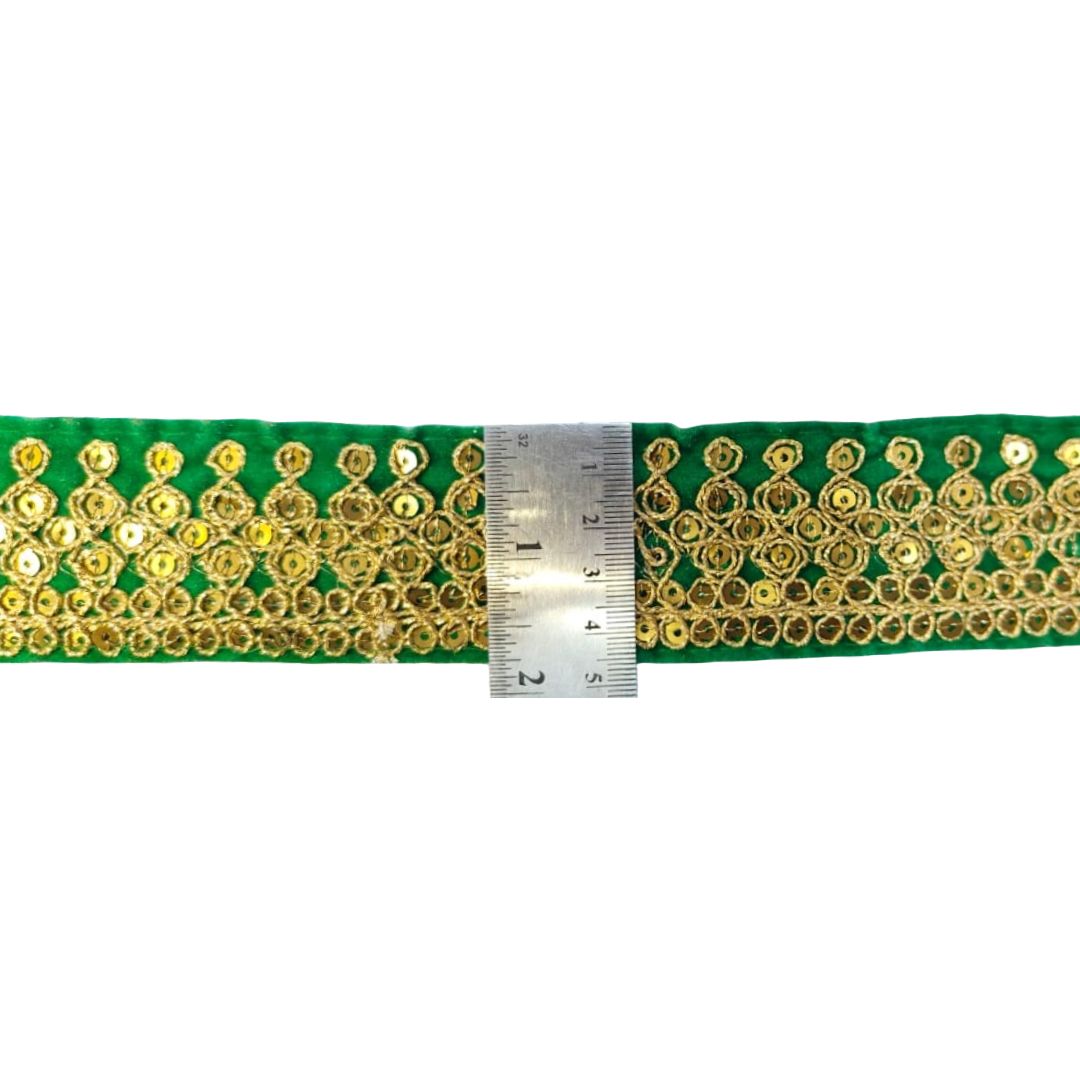 Green ribbon with gold embellishments and a ruler for scale on a white background