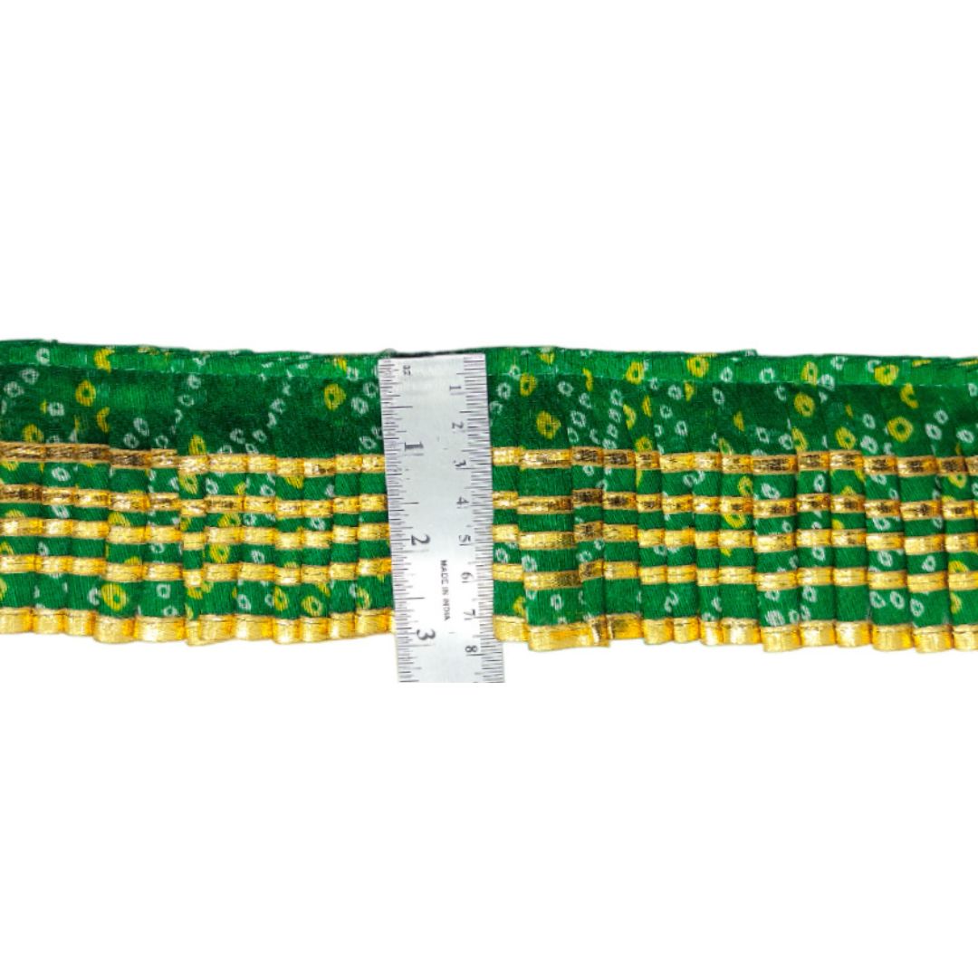 Green and yellow patterned fabric with a ruler for scale on a white background