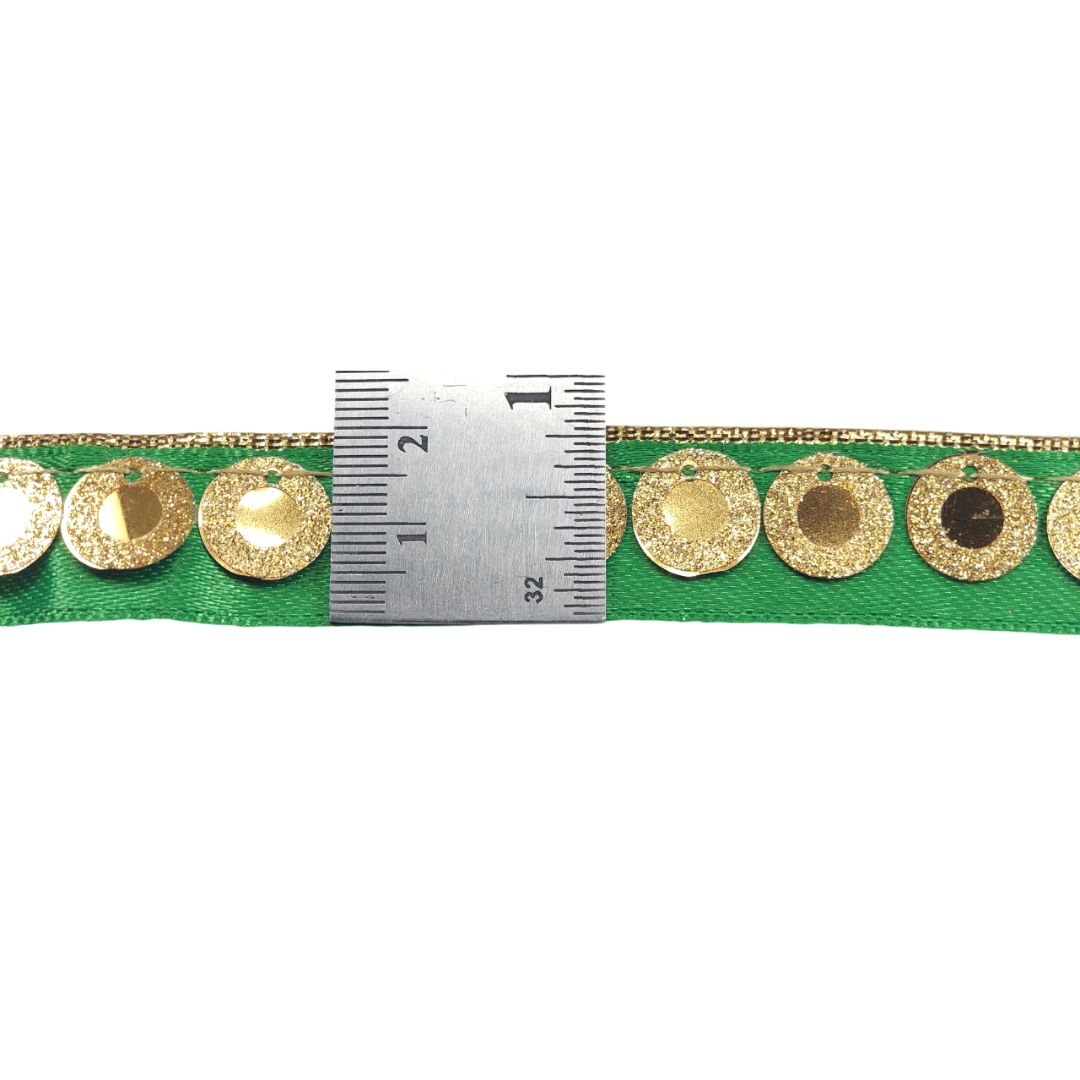 Green ribbon with gold circular patterns and a ruler for scale on a white background