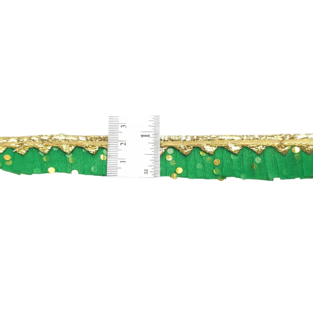 Green ribbon with gold edge and polka dots, measured against a ruler on a white background