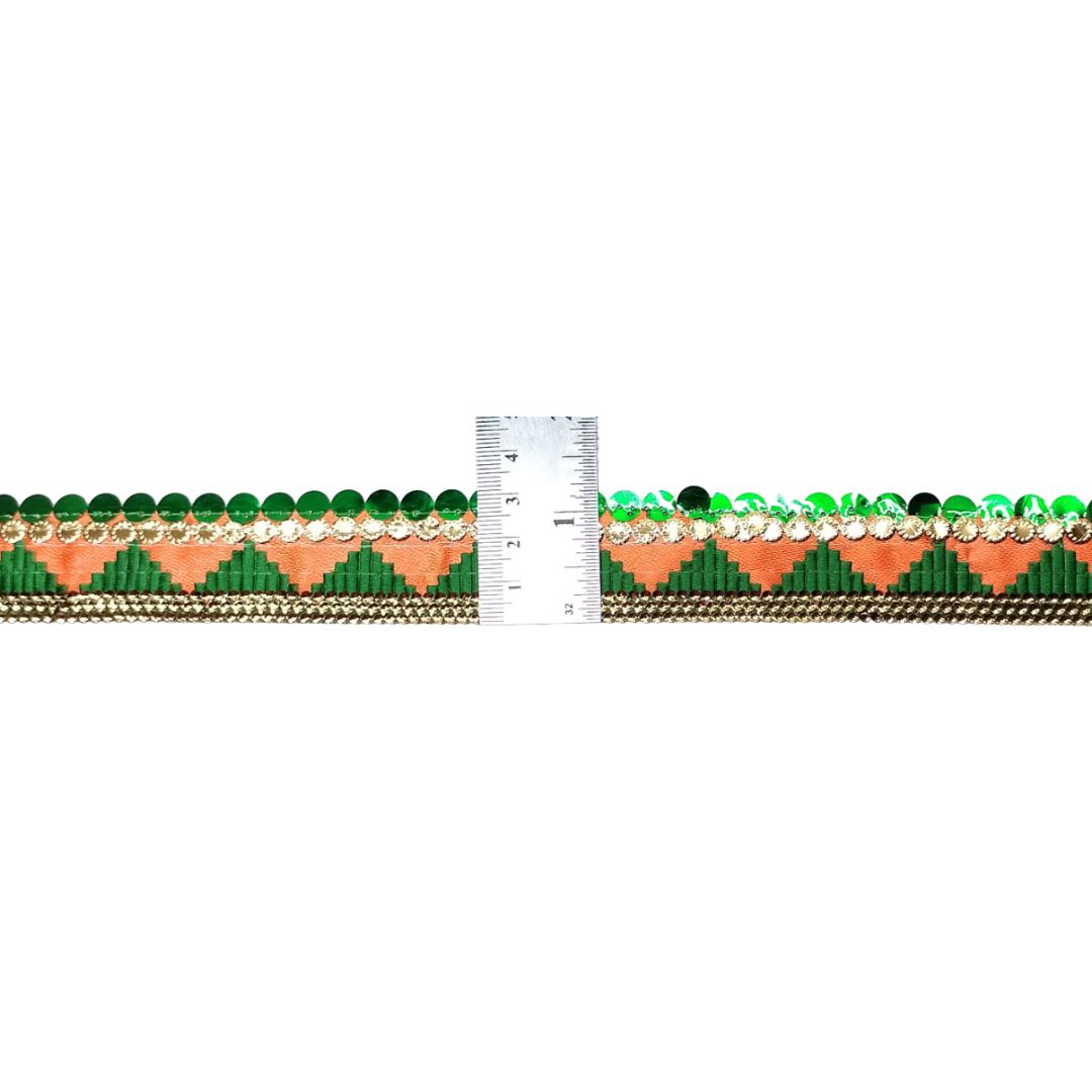 Decorative trim with green and peach pattern next to a ruler for measurement on a white background