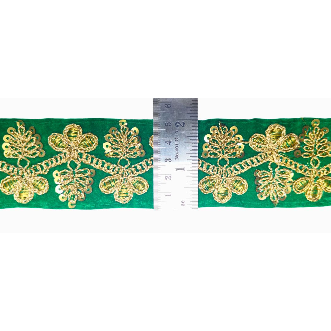 Green fabric with gold embroidery and a ruler for scale on a white background