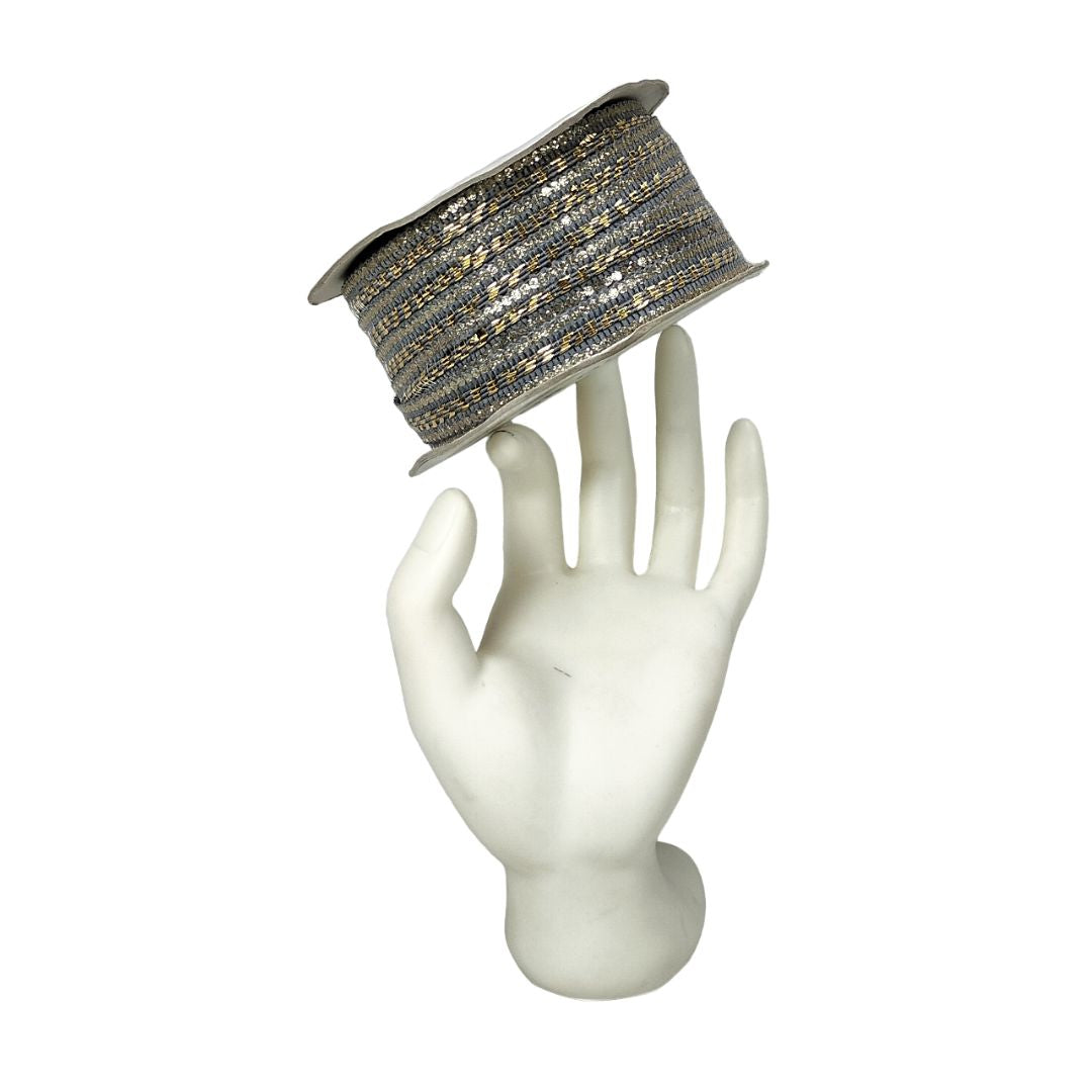 Decorative ribbon spool on a mannequin hand against a white background