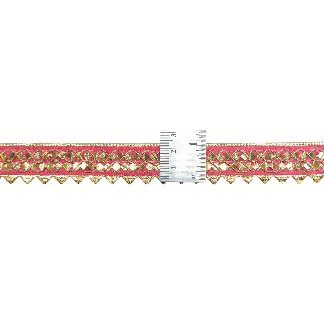 Decorative ribbon with gold pattern and pink background, measured against a ruler.
