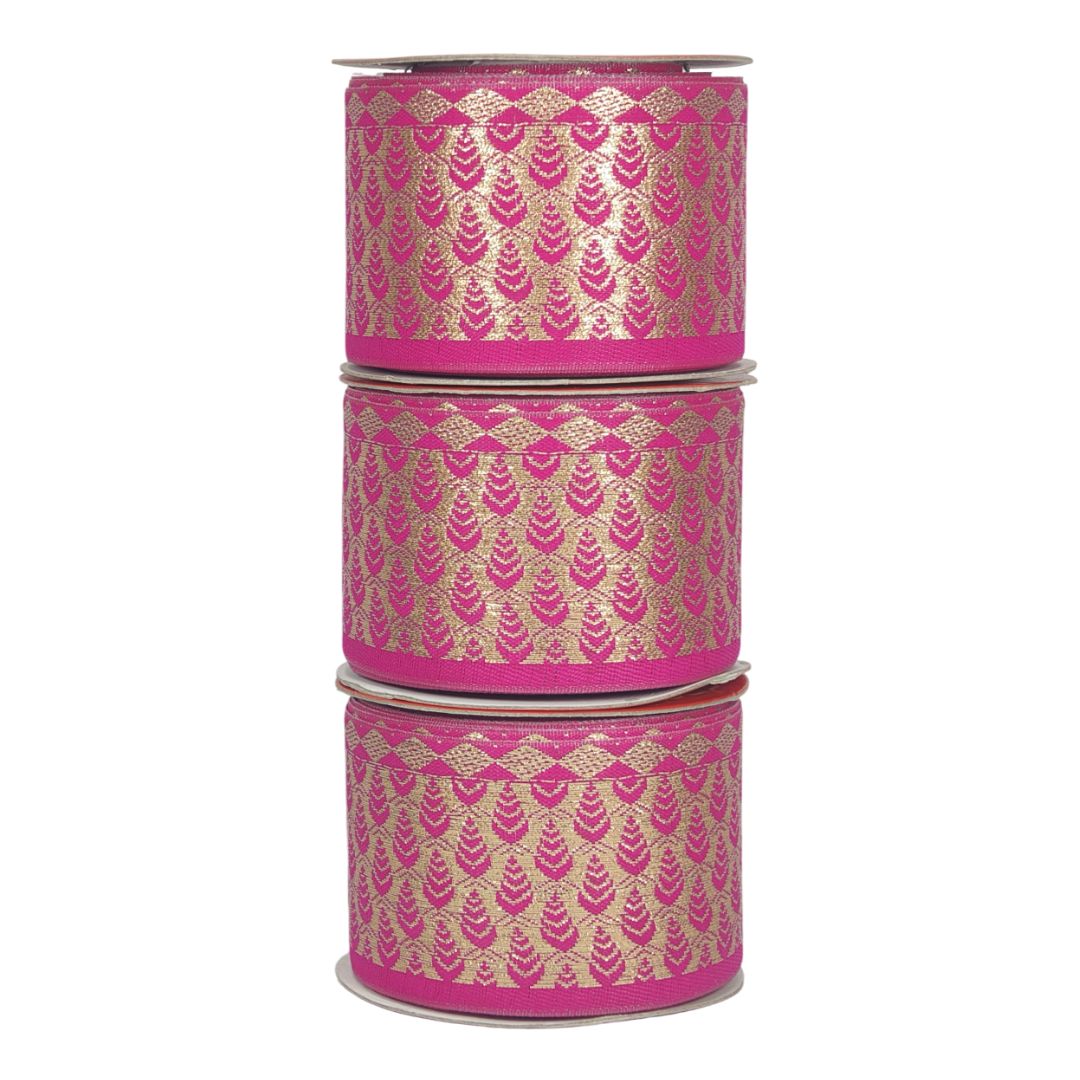 Three rolls of pink ribbon with gold patterns on a white background