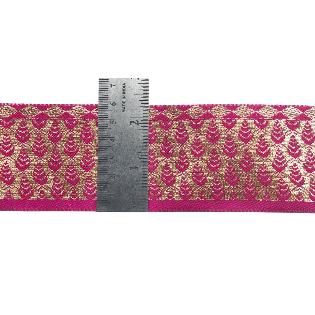 Decorative ribbon with gold pattern and pink border, measured against a ruler on a white background.