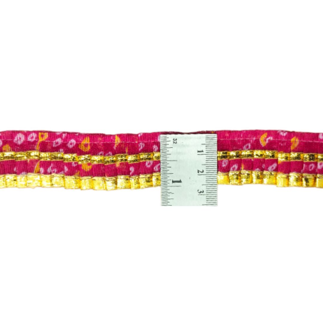 Pink and gold belt with a ruler for size reference on a white background