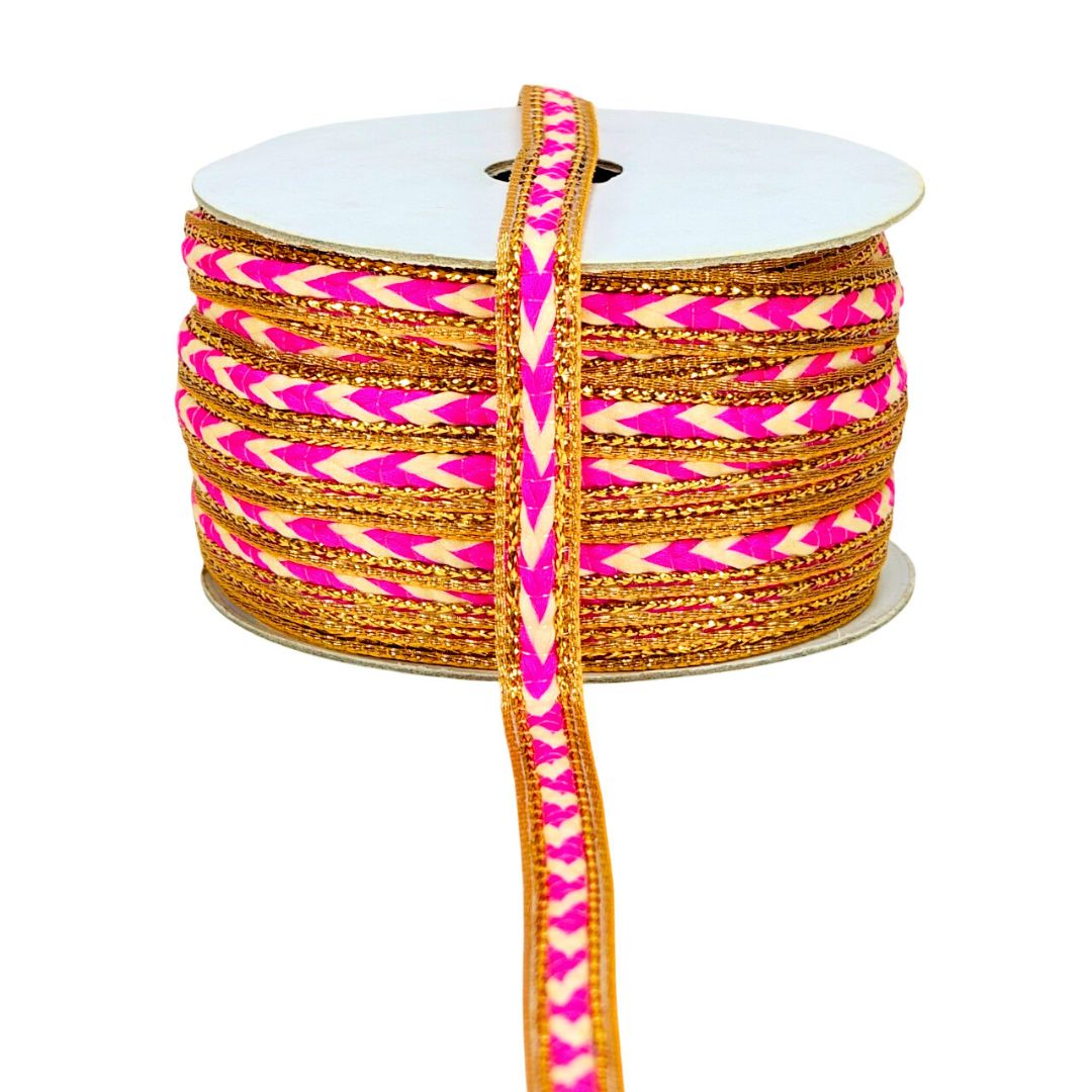 Spool of pink and gold ribbon with a zigzag pattern on a white background