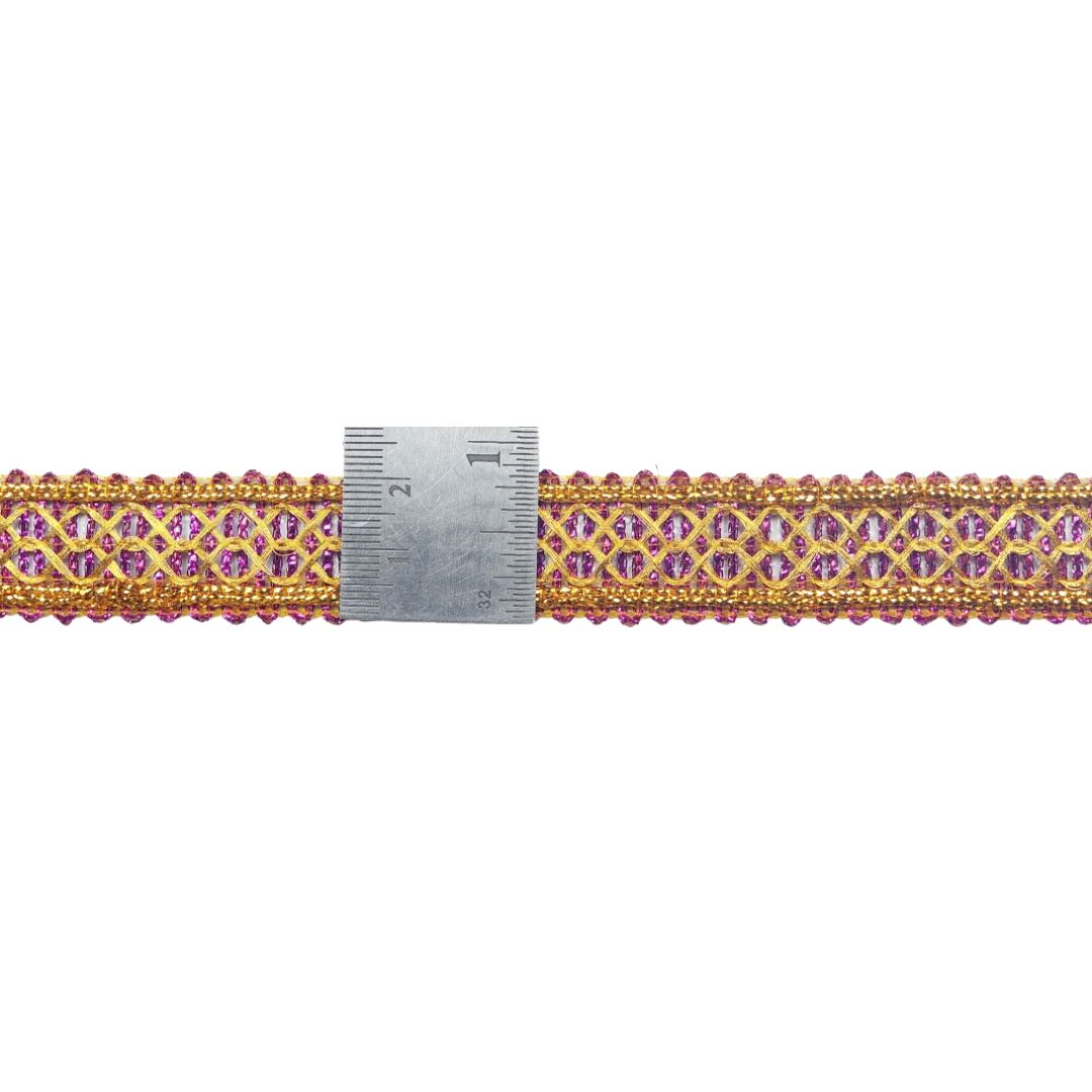 Decorative ribbon with pink and gold pattern next to a ruler on a white background