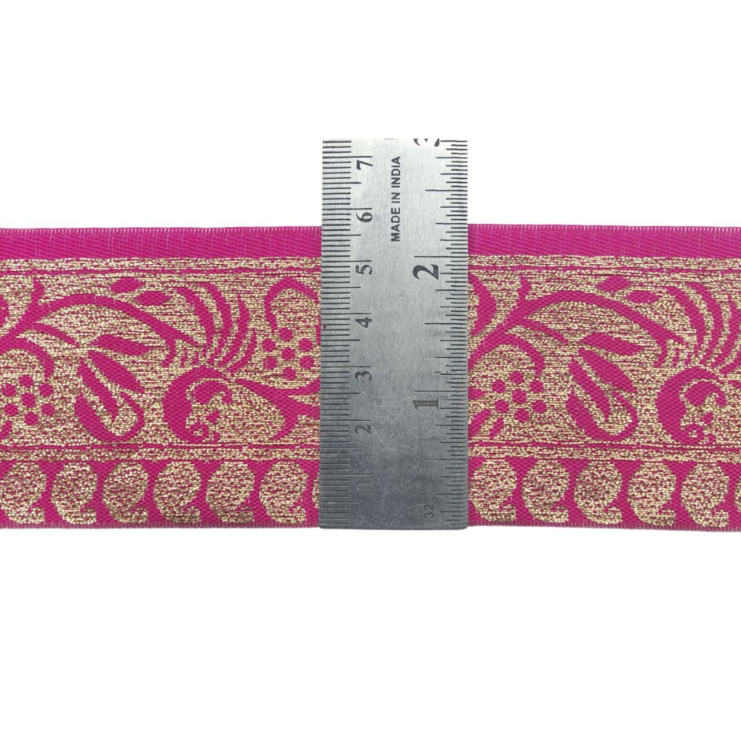 Decorative ribbon with pink and gold pattern and a ruler for scale on a white background