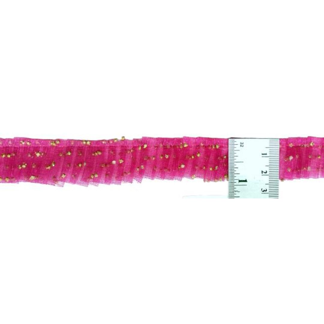 Pink tulle ribbon with gold glitter and a ruler for scale on a white background