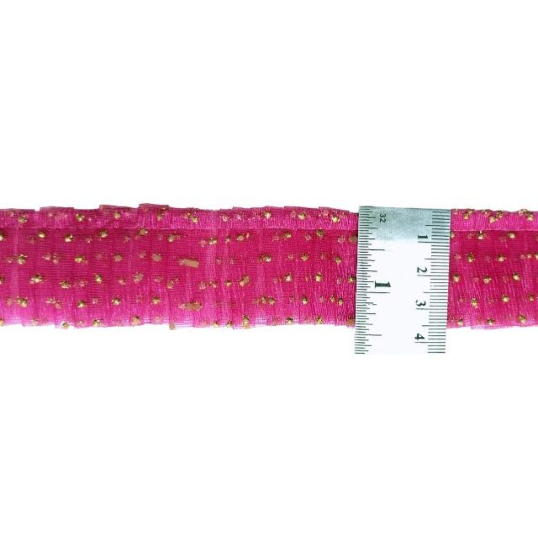 Pink ribbon with gold polka dots and a ruler for measurement on a white background