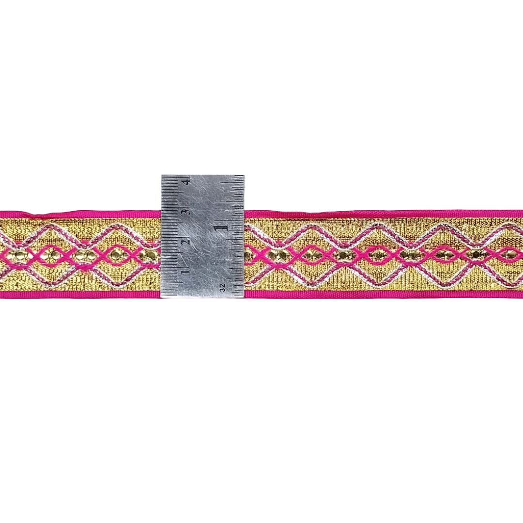 Decorative ribbon with pink and gold pattern and a ruler for scale on a white background