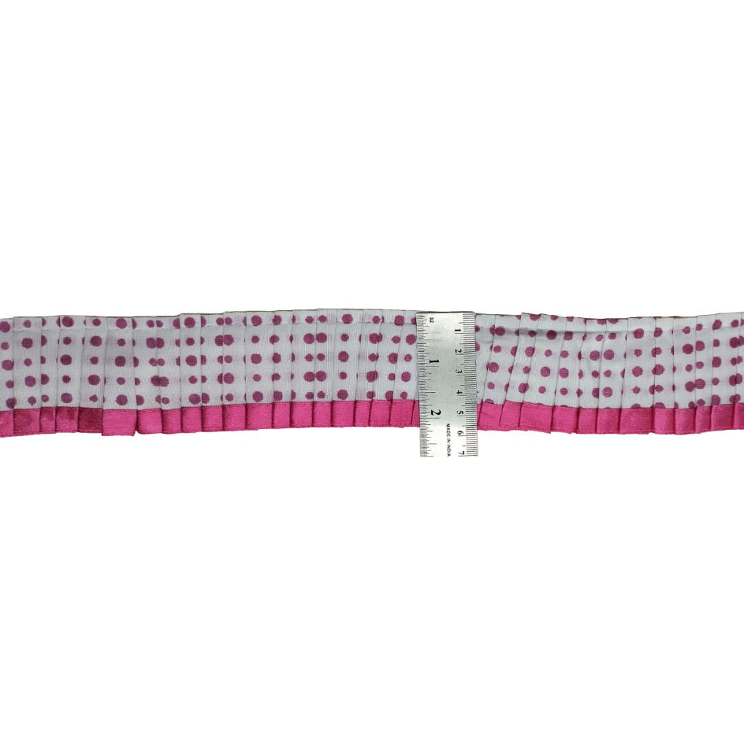 Polka dot ribbon with pink edge and ruler for scale on a white background